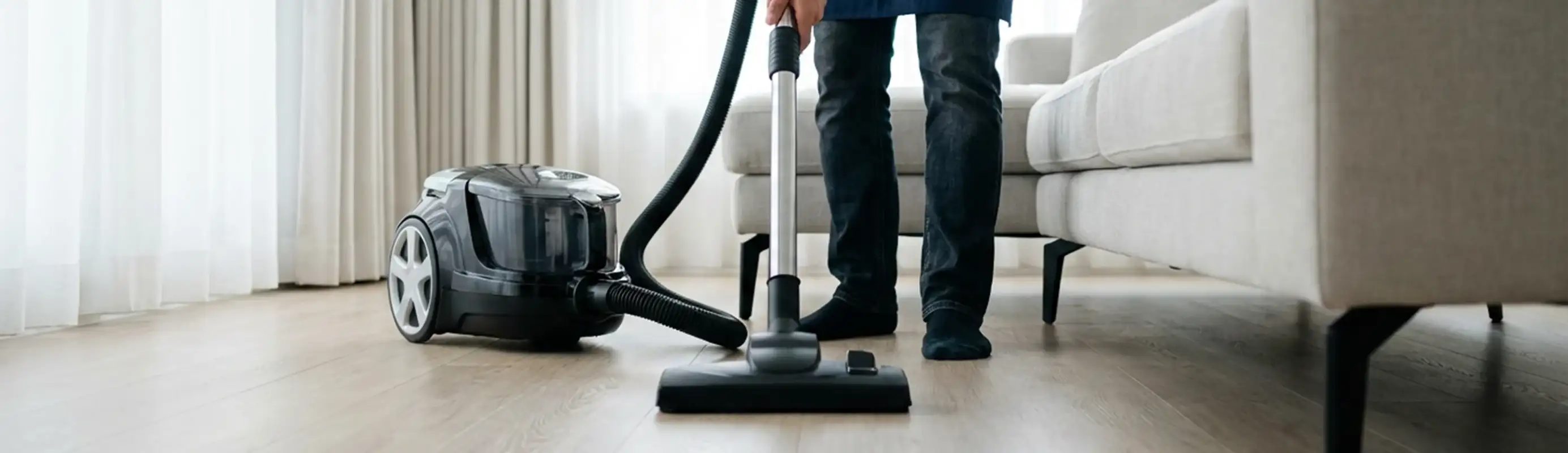 Professional house cleaner vacuuming a living room floor with a canister vacuum cleaner, Fort Wayne, IN.