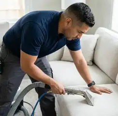 Professional upholstery cleaning technician using an extraction wand to deep-clean a fabric sofa, Fort Wayne, IN.