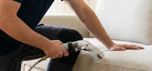 Professional upholstery cleaner deep-cleaning a fabric sofa with a handheld extraction tool, Fort Wayne, IN.